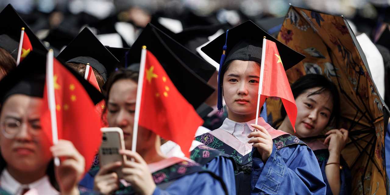 Students from Wuhan University hold flags during the graduation ceremony in the school's stadium on June 20, 2023 in Wuhan.