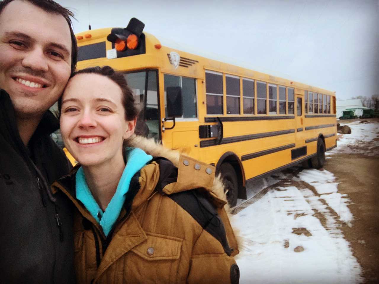 a couple takes a selfie with a school bus