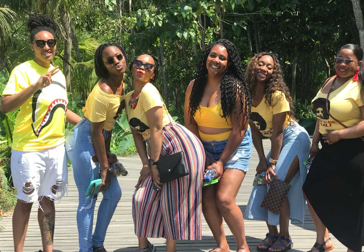 Group of women posing in yellow shirts in front of trees in Bali.