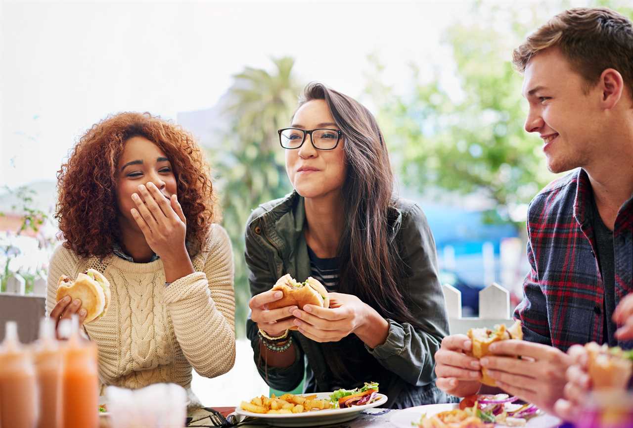 Three young people eating burgers