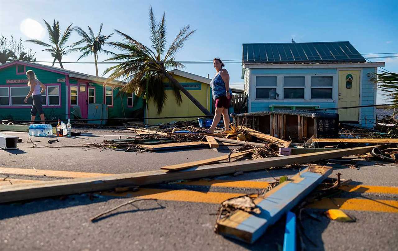 A woman surveys damage from a hurricane.