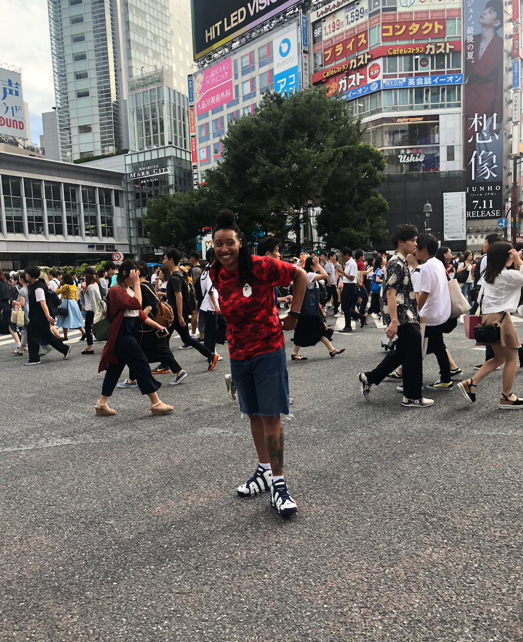 Woman standing in a crowded street in Tokyo with buildings behind her.