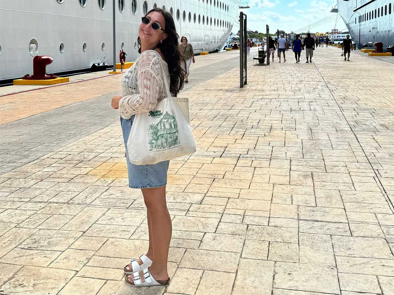 jordana posing in front of a cruise ship carrying a tote bag