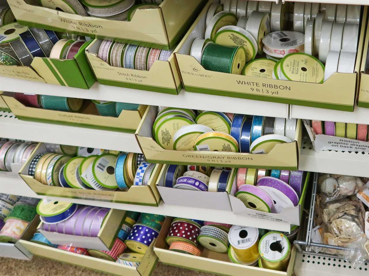 Assorted ribbons in various colors and patterns in beige boxes at Dollar Tree