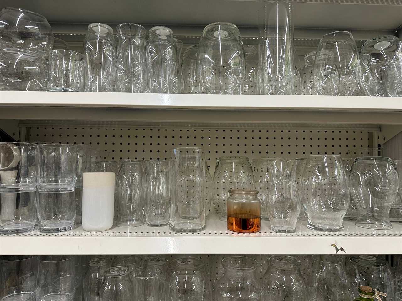 Several vases in various shapes on shelves at Dollar Tree. The vases are clear glass