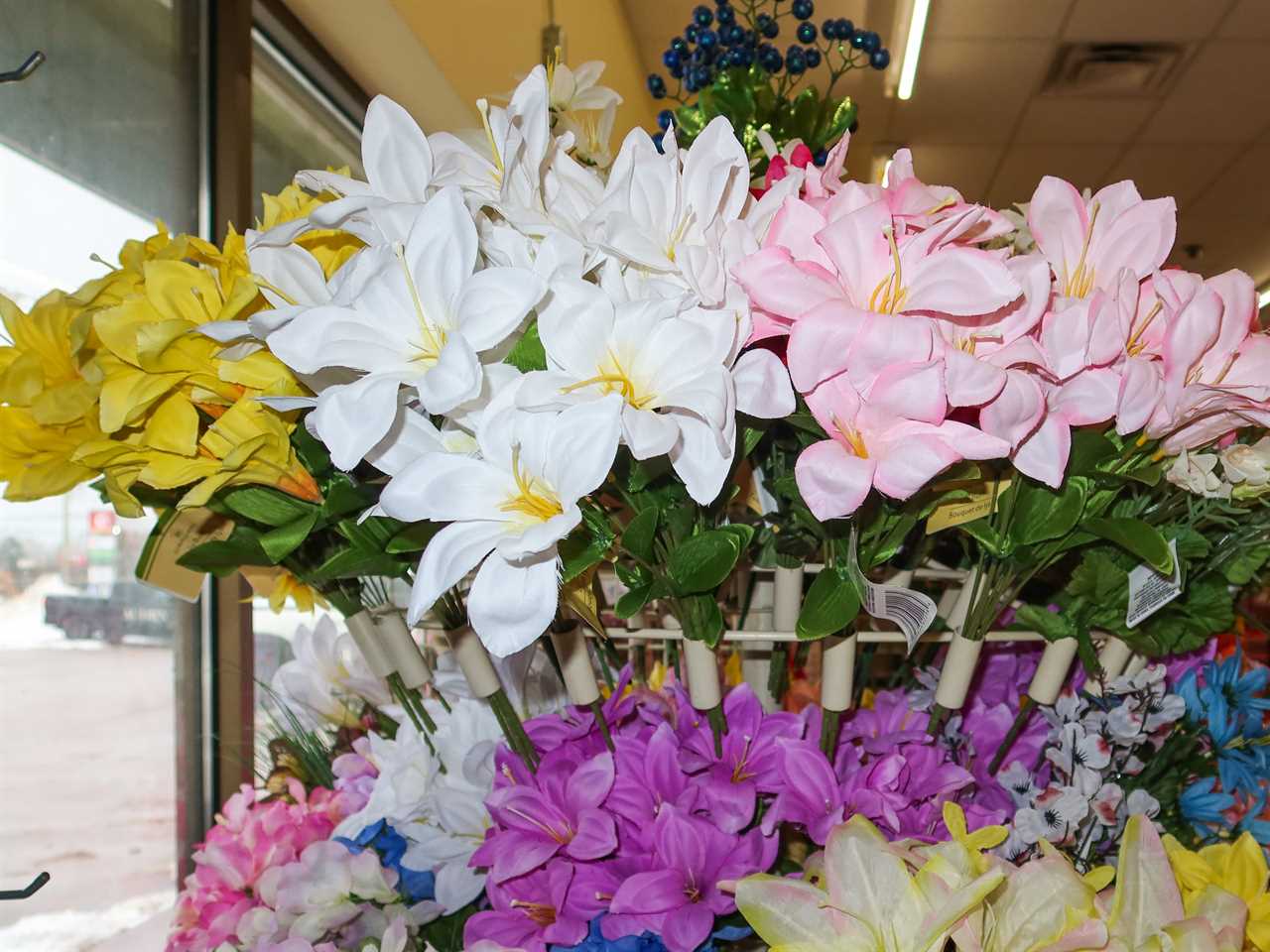 Faux flowers on a display at Dollar Tree. They come in purple, yellow, pink, and white colors