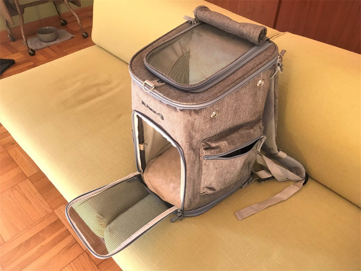 A gray Mr. Peanut's backpack pet carrier with open mesh door and top is shown on a sofa.