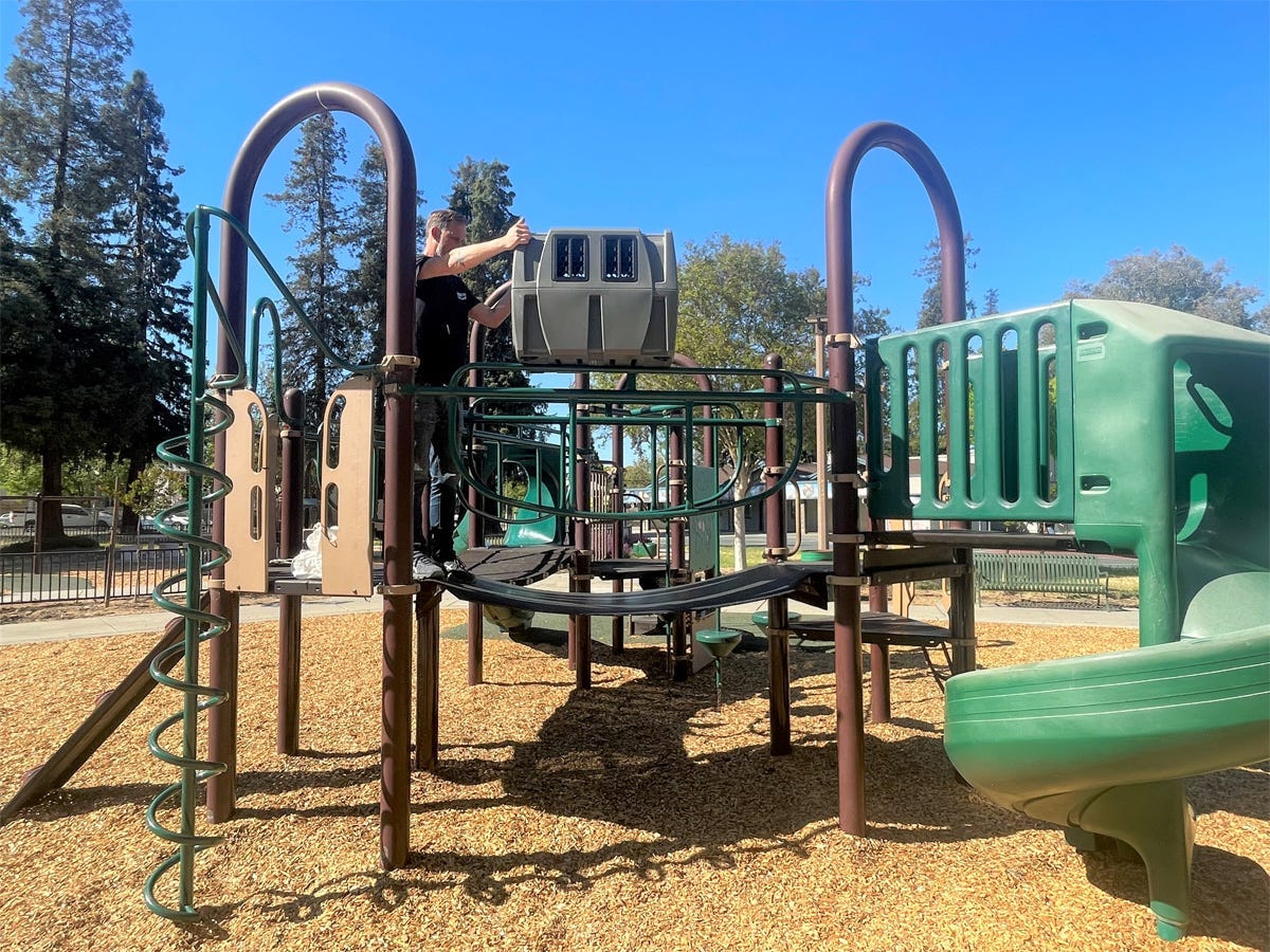 A person is throwing an empty airplane pet kennel off of the landing of a playground gym.