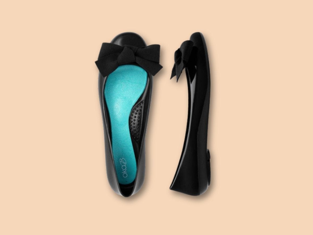 Rubber black Oka-B Pollie ballet flats with blue soles on a beige background