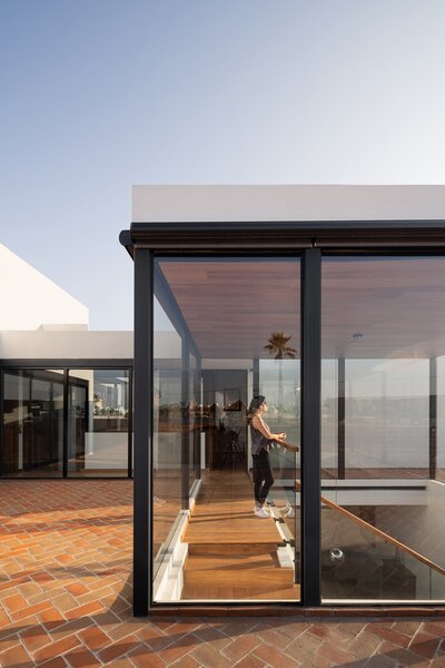 At Casa Cantellano, a class cube sits atop the second level, drawing daylight to the dining room below. The cube meets the owners two hobby rooms in the middle, with one wing for reading and another for film and games.