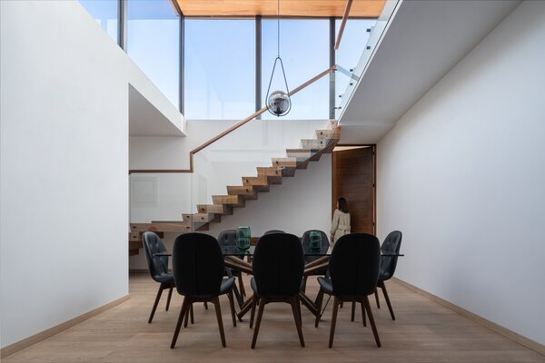 The dining room sits at the center of the home and receives floods of light from the glass cube above.