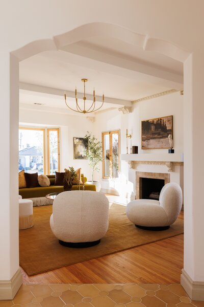 A curved archway opens to the living area, which is anchored by tall, wood-trimmed windows and a brick fireplace.