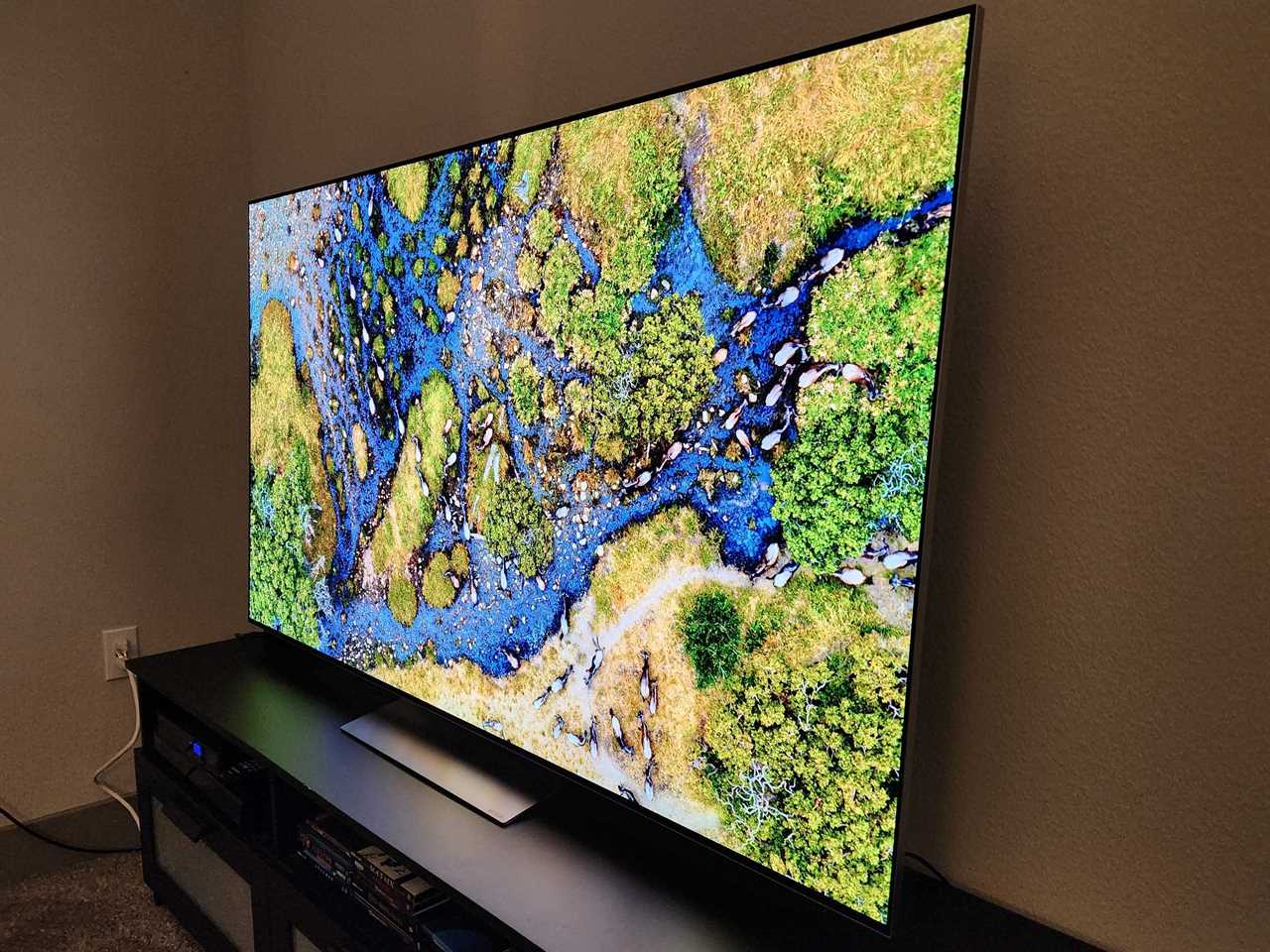 An angled image of an LG G3 TV resting on an entertainment console while displaying a river on the screen.