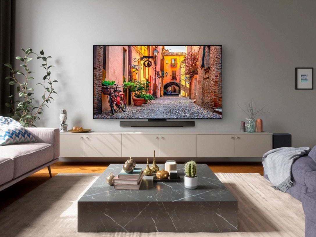 An LG C3 OLED hanging on a wall above a soundbar and TV stand in a living room.