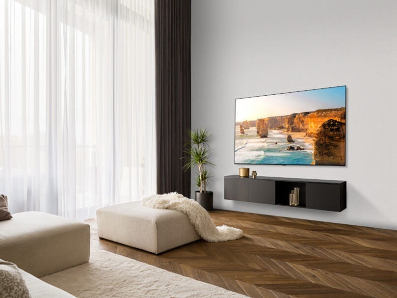 An LG B3 OLED TV hanging on a wall above a TV stand in a living room