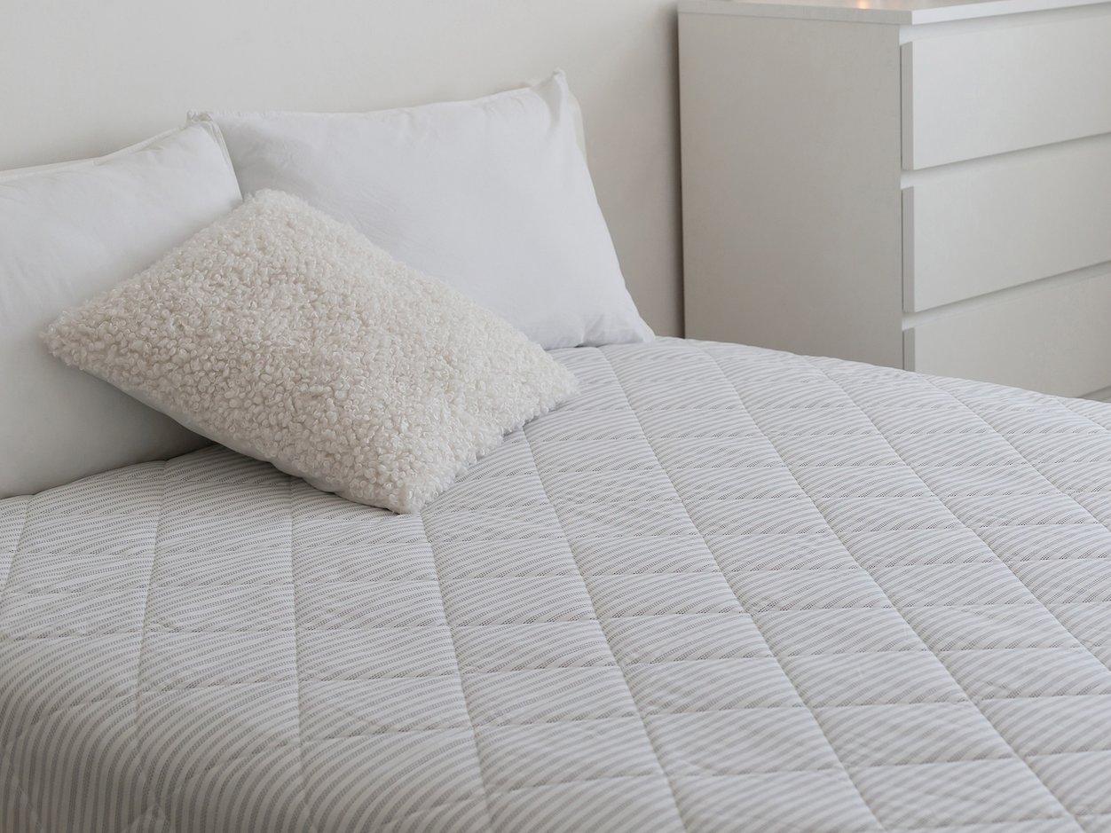 minimal white bedroom with a bare mattress on the bed