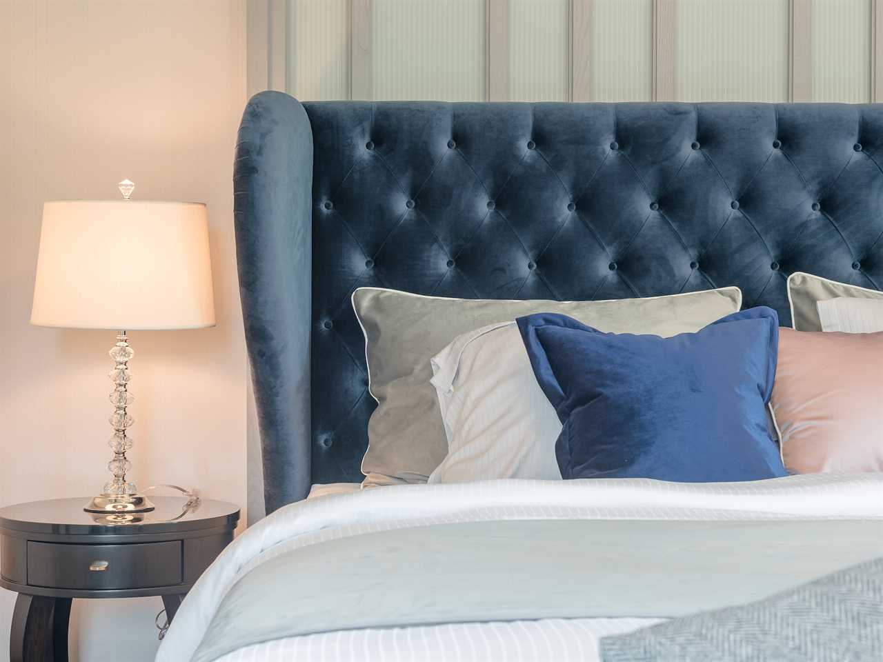 modern bed with a big blue upholstered headboard and blue and pink throw pillows