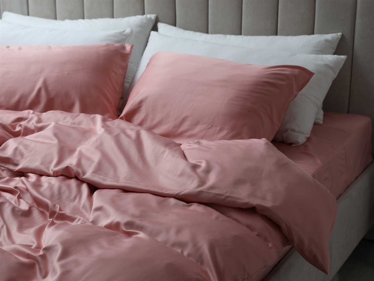 bed with pink silk linens and white fluffy pillows