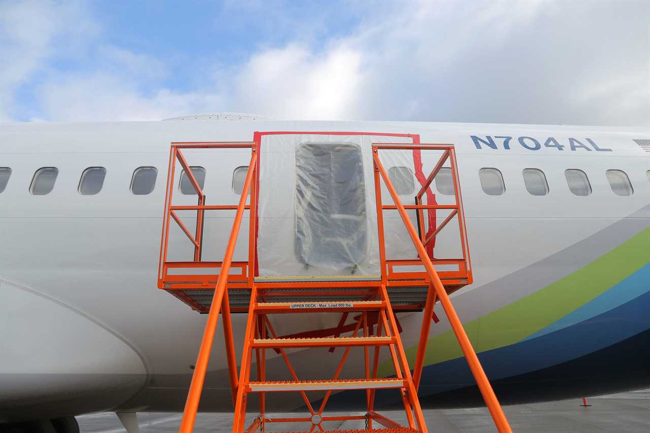 Plastic covers the exterior of the fuselage plug area of Alaska Airlines Flight 1282