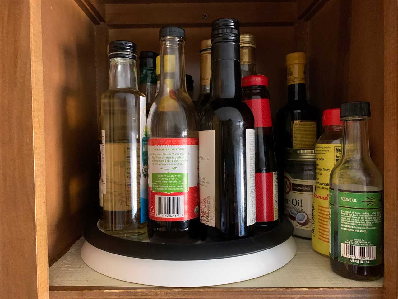 Several sauce bottles are stored on the OXO lazy susan in a cupboard, for a review of the OXO Lazy Susan in 2022.