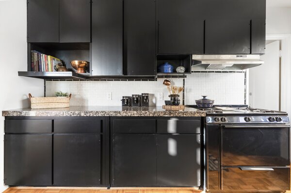 The kitchen is fitted with sleek black cabinetry which pops against the white backsplash.