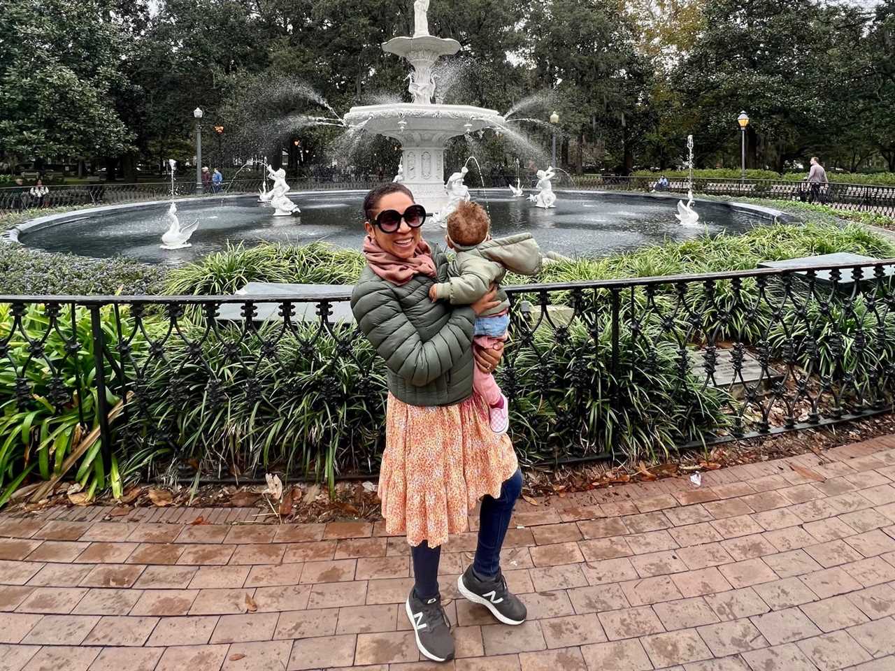 Stephanie Claytor and her child smiling in front of a fountain.