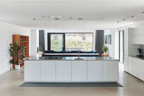 The light-filled kitchen features custom bespoke cabinetry, along with a large central island that delineates the space from the adjacent dining area.