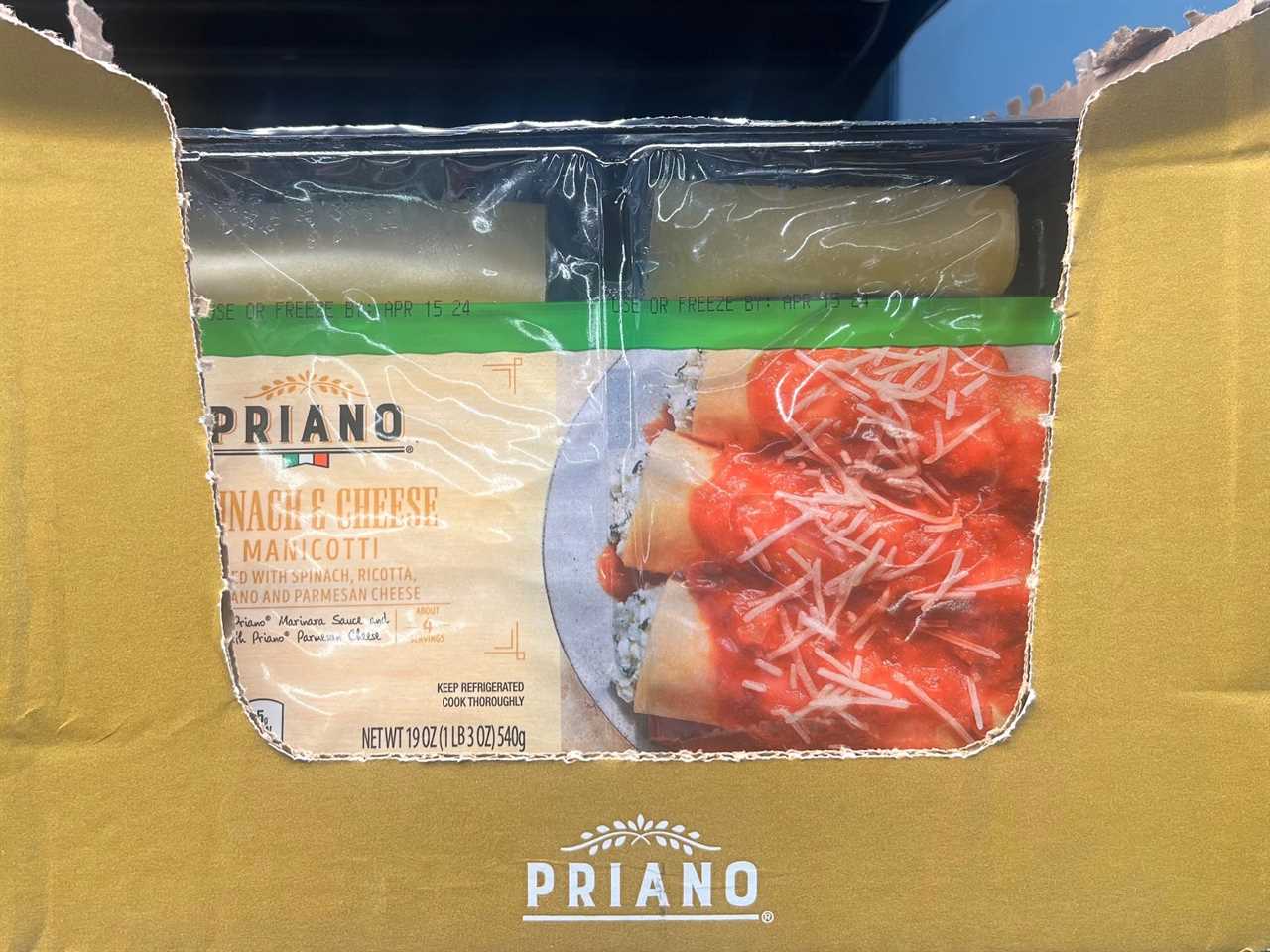 Package of Priano spinach and cheese manicotti with an image of pasta and red sauce on a plate. Package is inside a yellow cardboard box