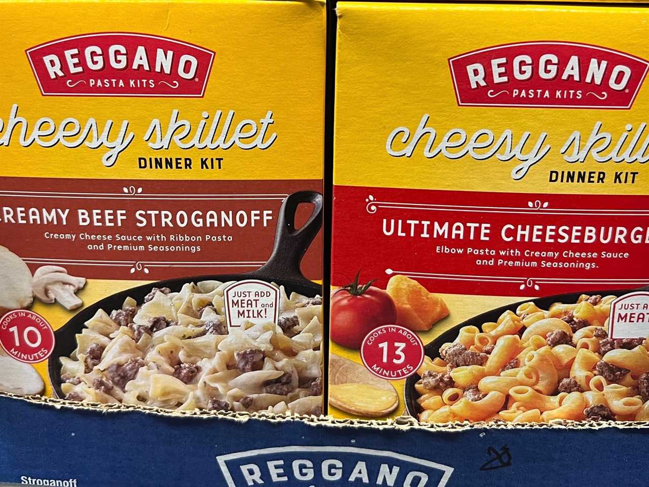 Yellow boxes of Reggano cheesy skillet dinners with images of creamy beef stroganoff and ultimate cheeseburger on boxes