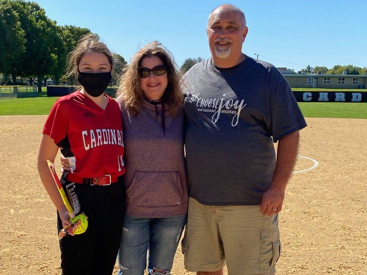 shannon serpette with her daughter and husband on a baseball diamond