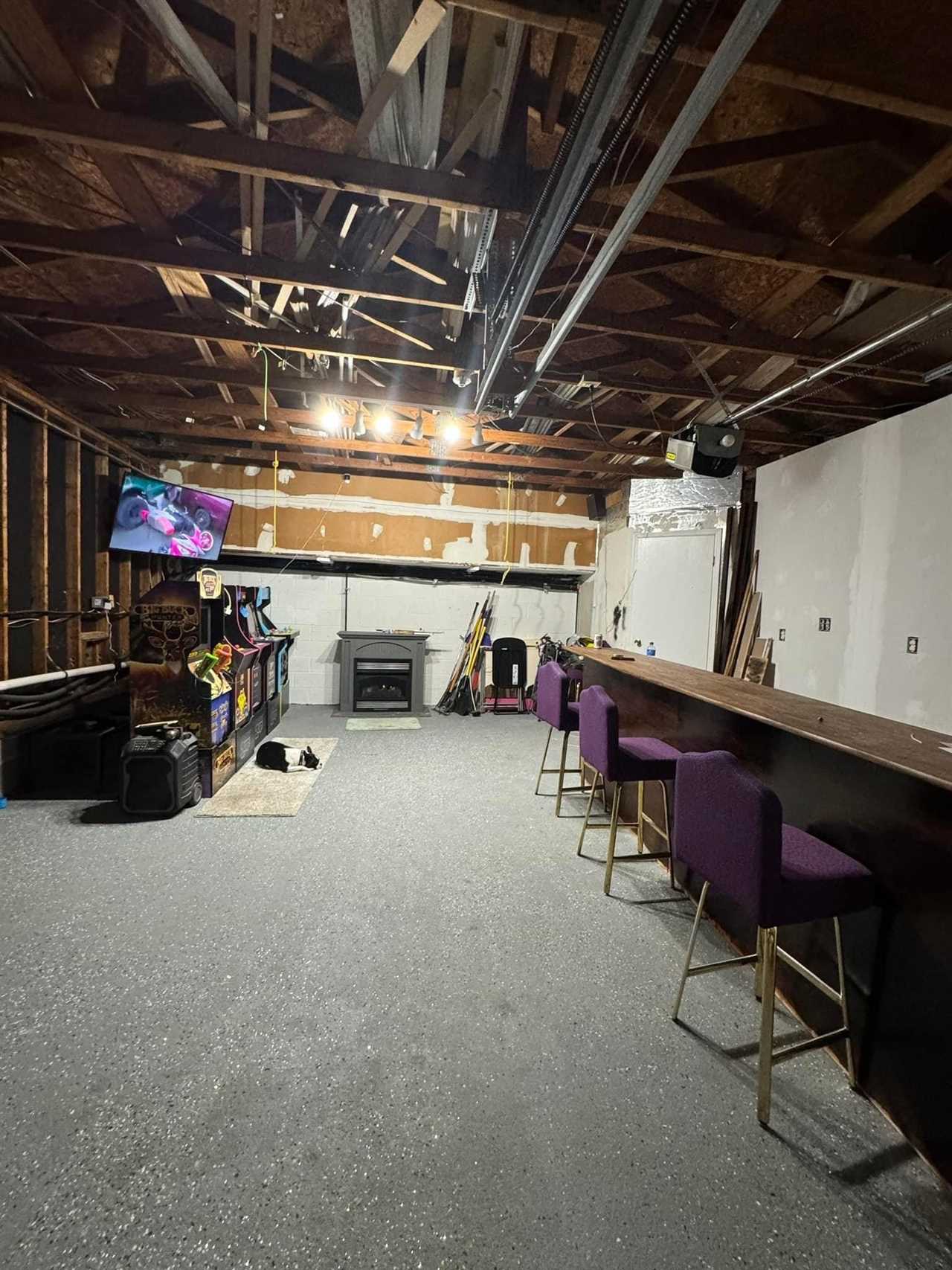 A garage under renovation with a bar and arcade games.