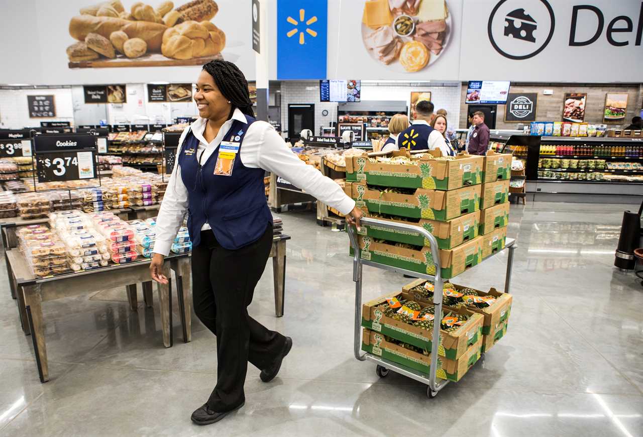 Candais Pipkin, produce department manager, wheels a cart of pineapples across a Walmart store.