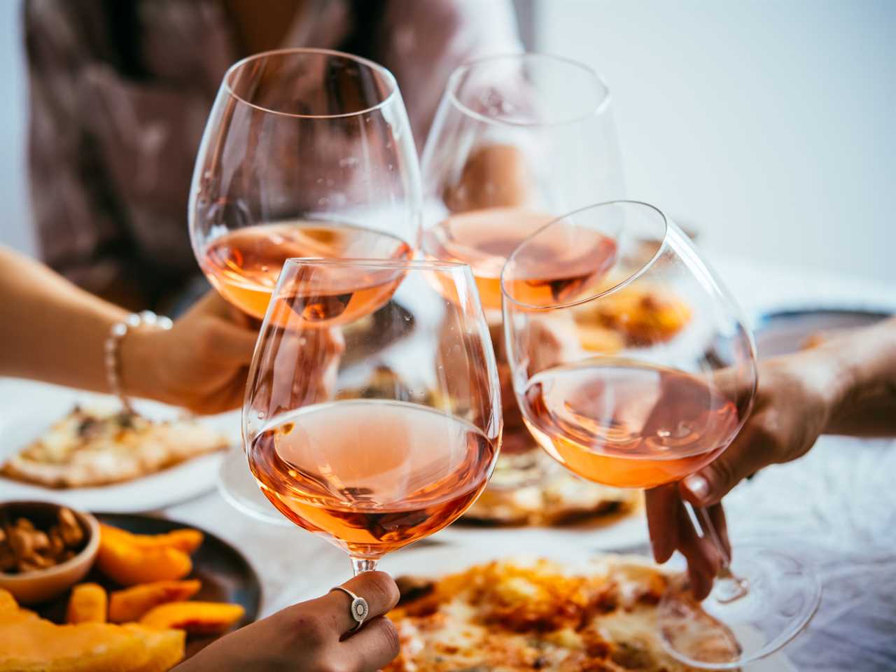 four people around a table of food cheering big glasses of rose