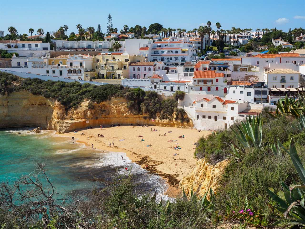 A view of people on the beach in southern Portugal with homes in the background.