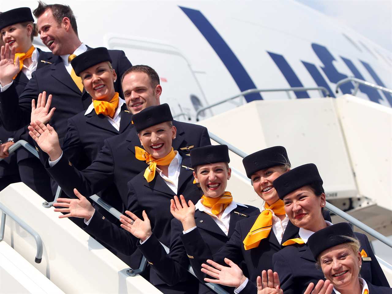Flight attendants wave in hats and scarves in 2012.