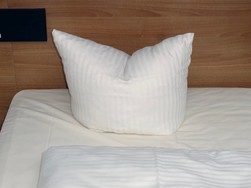 German bed pillow with crease down center in a bed