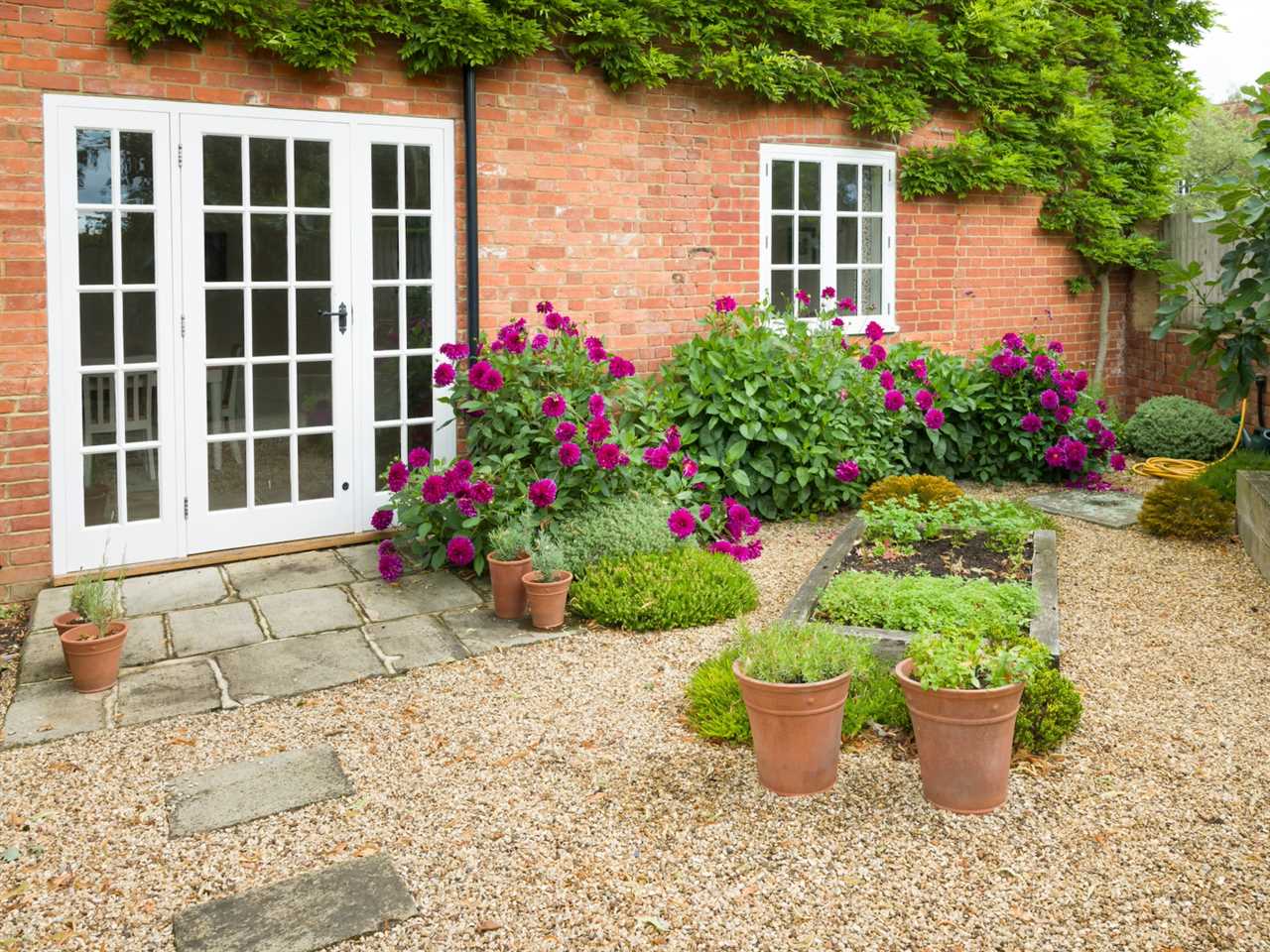 UK house and garden with patio and French doors. Cottage or courtyard garden (backyard) with gravel and York stone paving