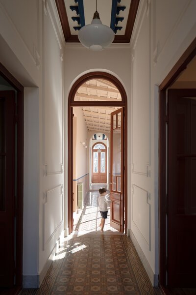 Artist Julián Benedit Prebisch and designer Micaela Suide bought a casa chorizo—a colonial housing type with rows of rooms that connect to a central patio—in a town in Argentina’s rural Pampas region. The front door opens to a long hall with original floor tiles, where their son, Florian, plays.