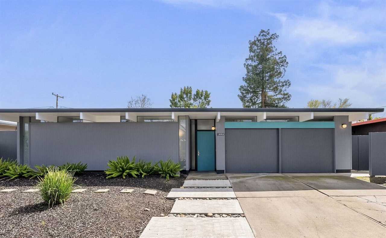 The home's bright blue front door pops against its gray-and-white exterior facade.