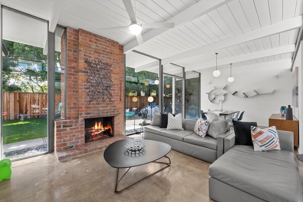 The original brick fireplace in the living room sits sandwiched between a wall of glass.