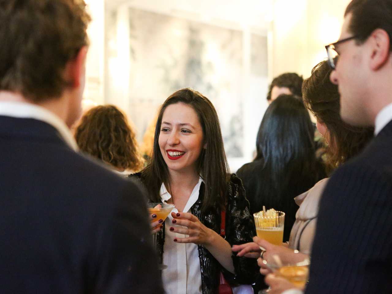 ana fota holding a drink while smiling in a crowd