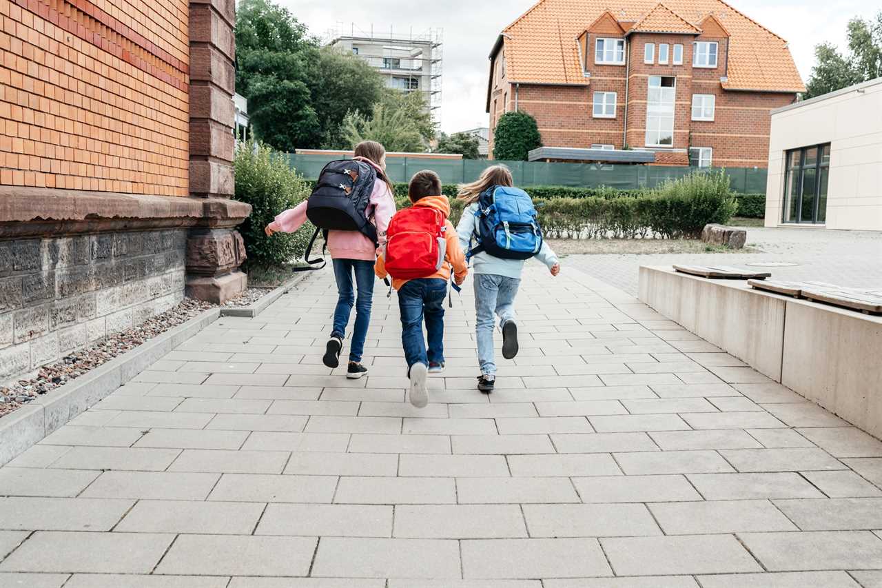 Schoolchildren with school bags on their backs joyfully rage home from school. End of classes and school year