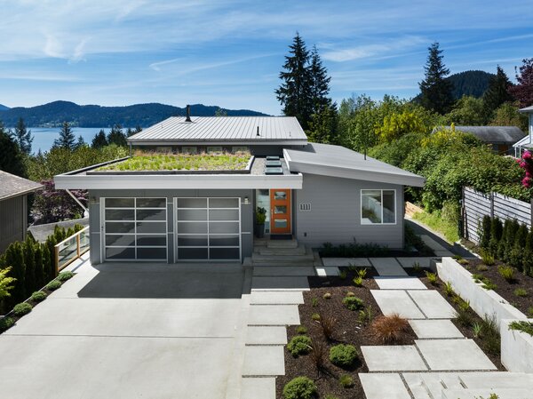 The home sports major curb appeal with its thriving green roof and bright orange front door.