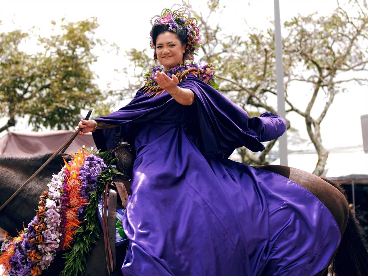 Woman riding an adorned horse with flowers.