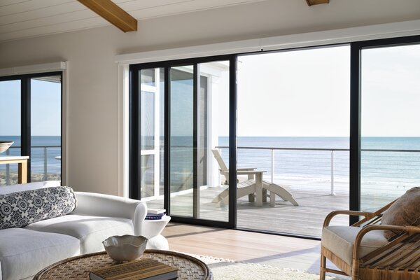 Wood beams, light oak-toned flooring,  a breezy white sofa and multi-slide doors from the Marvin Modern line complete the neutral living room.