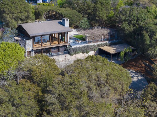 A long paved driveway winds up to the home, which sits perched among soaring trees.