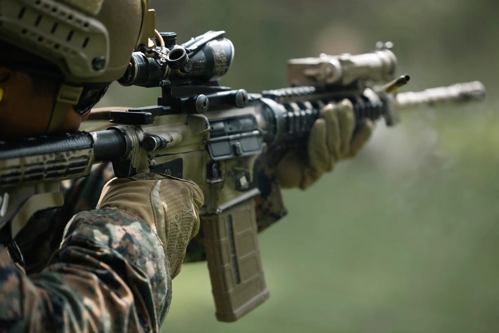 A close up shot of a US Marine firing an M4A1 carbine