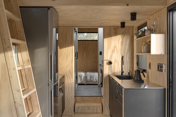 The tiny home features a condensed version of a full kitchen, which sits between a living and sleeping quarters.