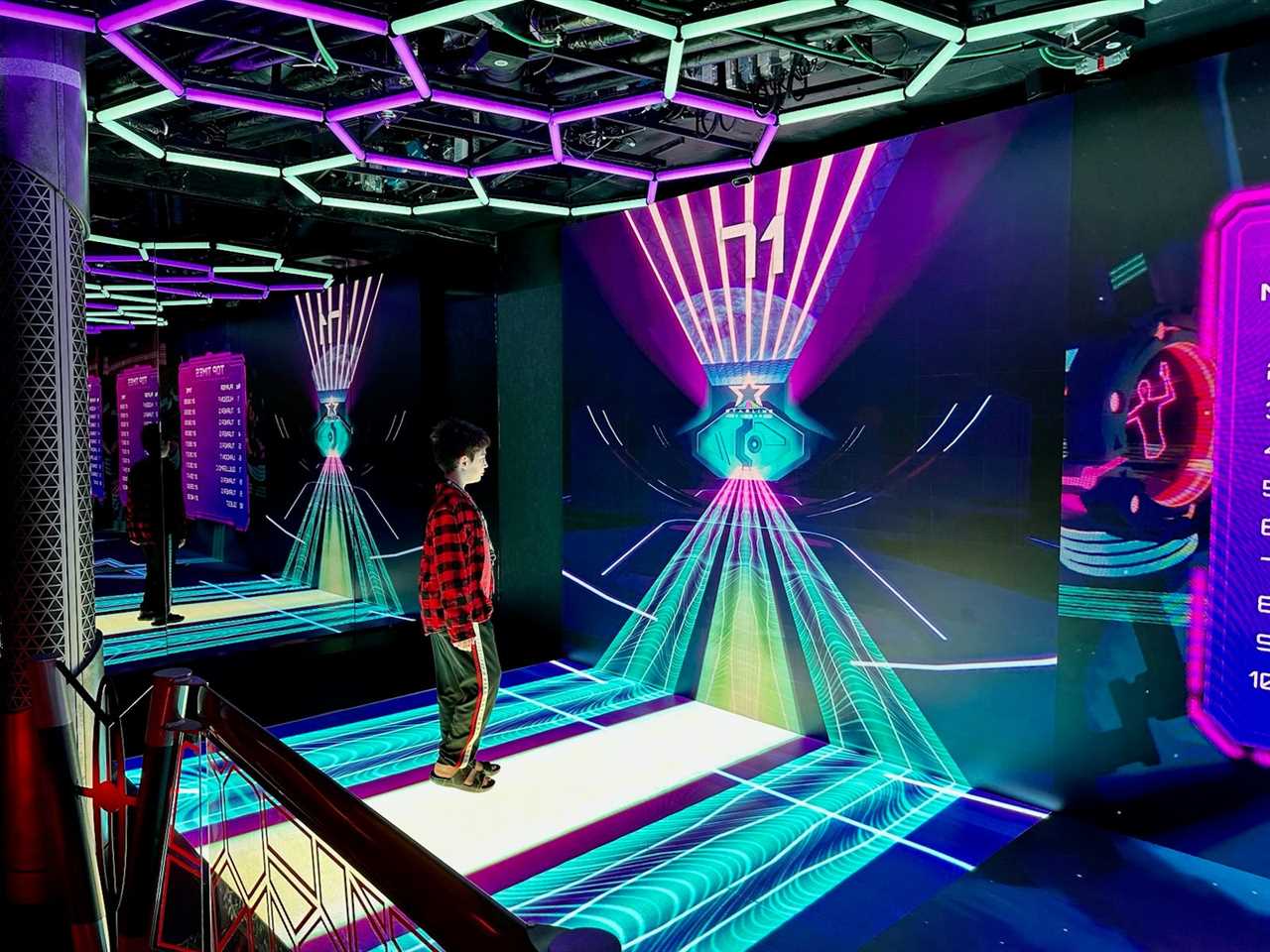 A boy playing virtual games on a giant light-up screen at a virtual-reality arcade