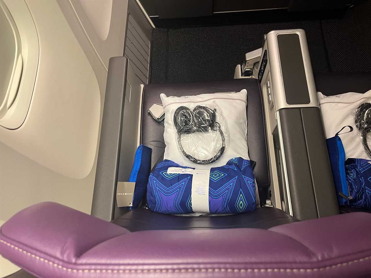 headphones, a pillow, and a blanket on an airplane seat